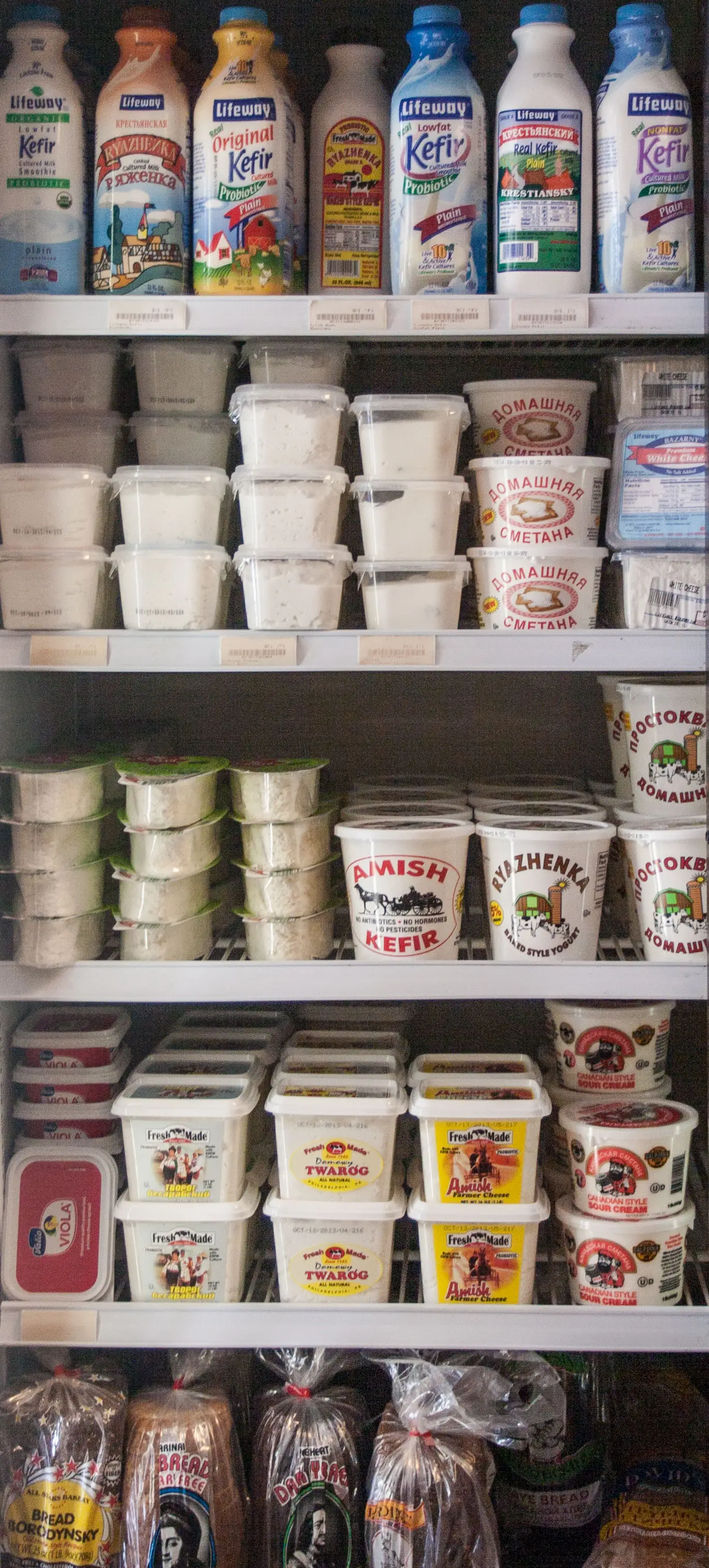 Kefir, sour cream, dairy products, and rye bread stocked in a refrigerated case.